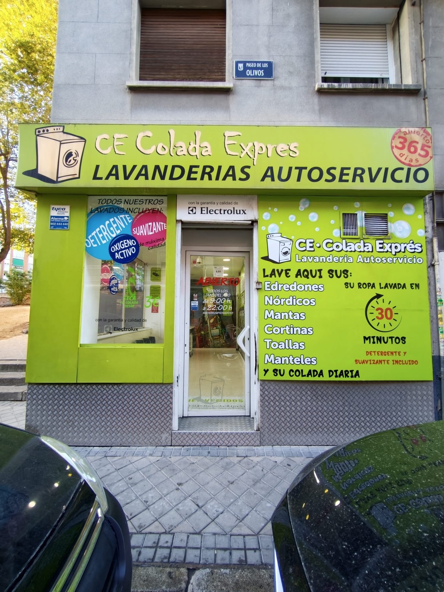 Fachada frontal de Colada Exprés en el barrio de Lucero, con el rótulo verde lima y la puerta de entrada