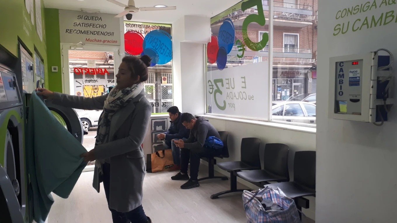 Clienta del barrio sacando su ropa de la lavadora en Colada Exprés, en Lucero
